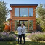 Portrait view of a couple from behind, looking at a stylish accessory dwelling unit (ADU) in a San Jose garden featuring lavender plants and olive trees under a clear blue sky