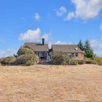 Custom home facade surrounded by dry pasture and blue sky in San Jose.