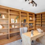 Executive home office with floor-to-ceiling built-in wooden bookshelves in San Jose 5-bed home.
