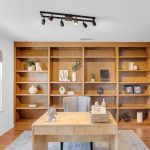 Custom home office desk and wall-to-wall wood shelving in luxury San Jose estate.