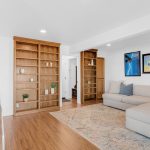 Open-concept secondary living room with light wood floors and custom shelving in San Jose CA.
