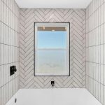 Soaking tub with white subway tile surround and window view in San Jose luxury bathroom.