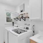 Remodeled laundry room with washer, dryer, white cabinets, and sink in San Jose home.