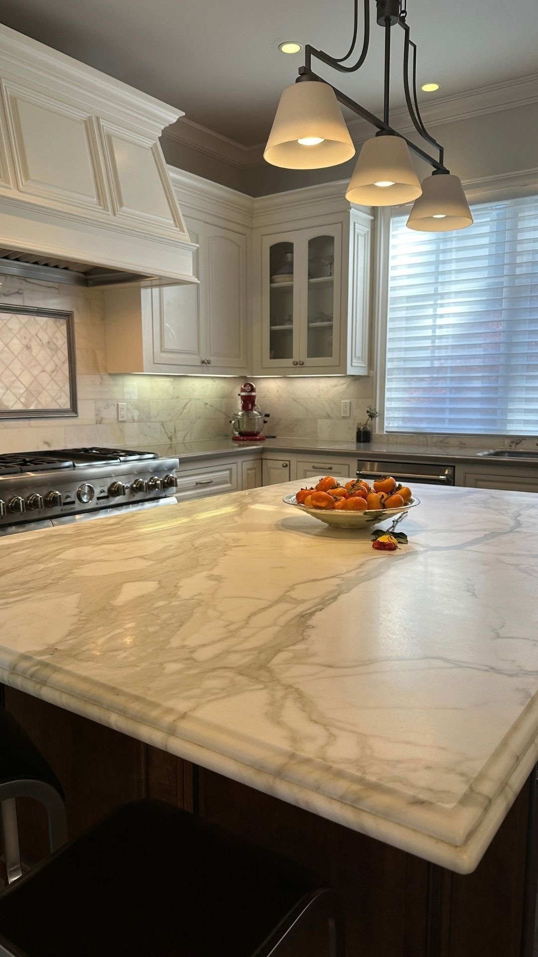 Modern luxury kitchen with a large marble kitchen island, high-end appliances, and warm pendant lighting in a San Jose real estate property.